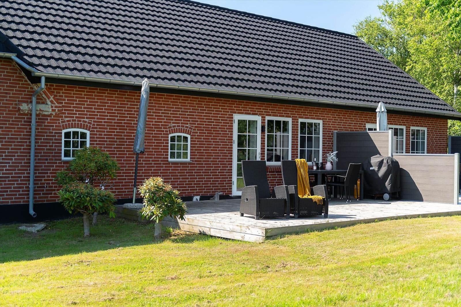 Rotes Backsteinhaus mit Terrasse, Garten und Außensitzgelegenheiten.