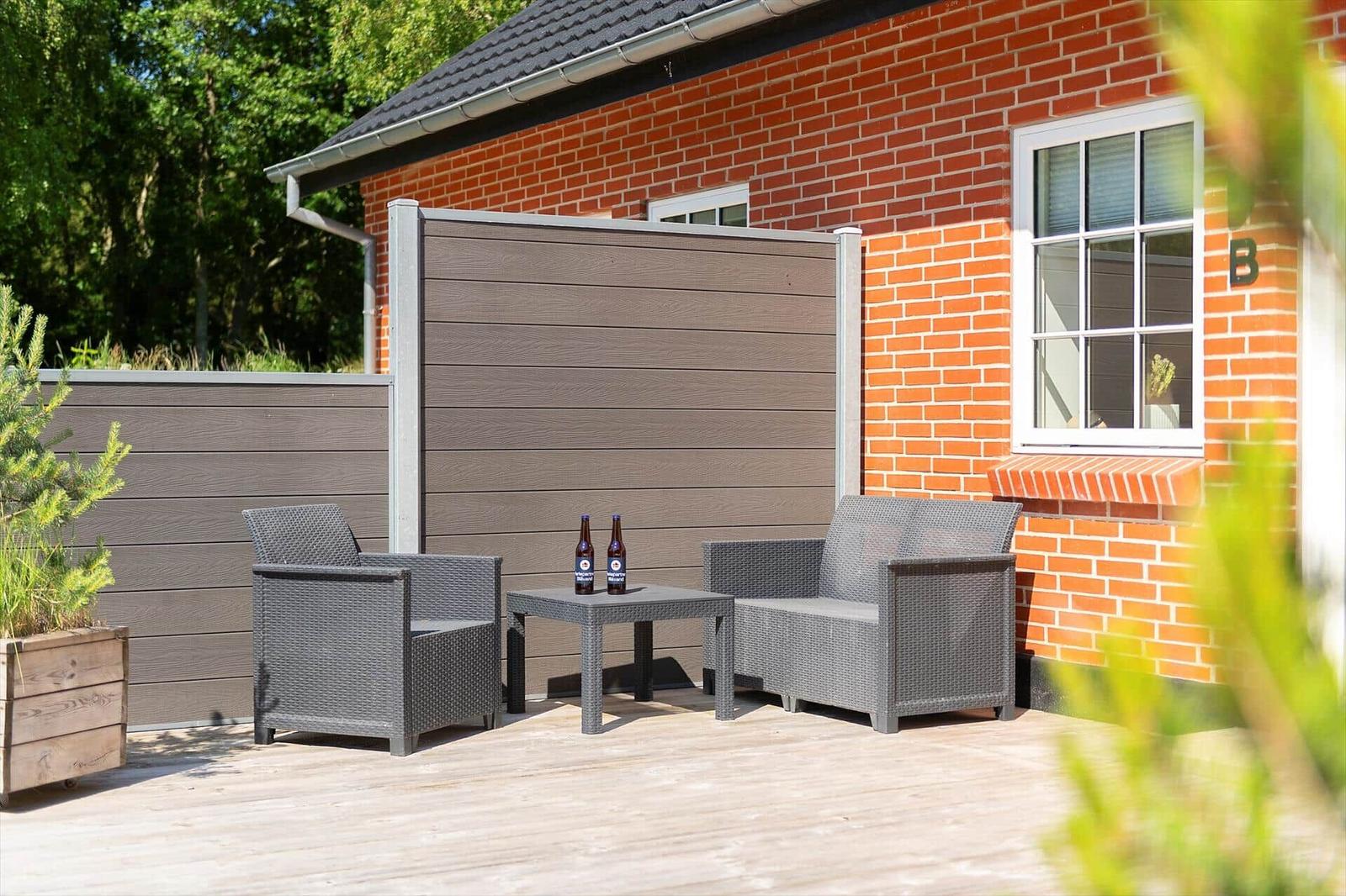 Terrasse mit zwei Sitzgelegenheiten und Tisch vor einem Backsteinhaus.