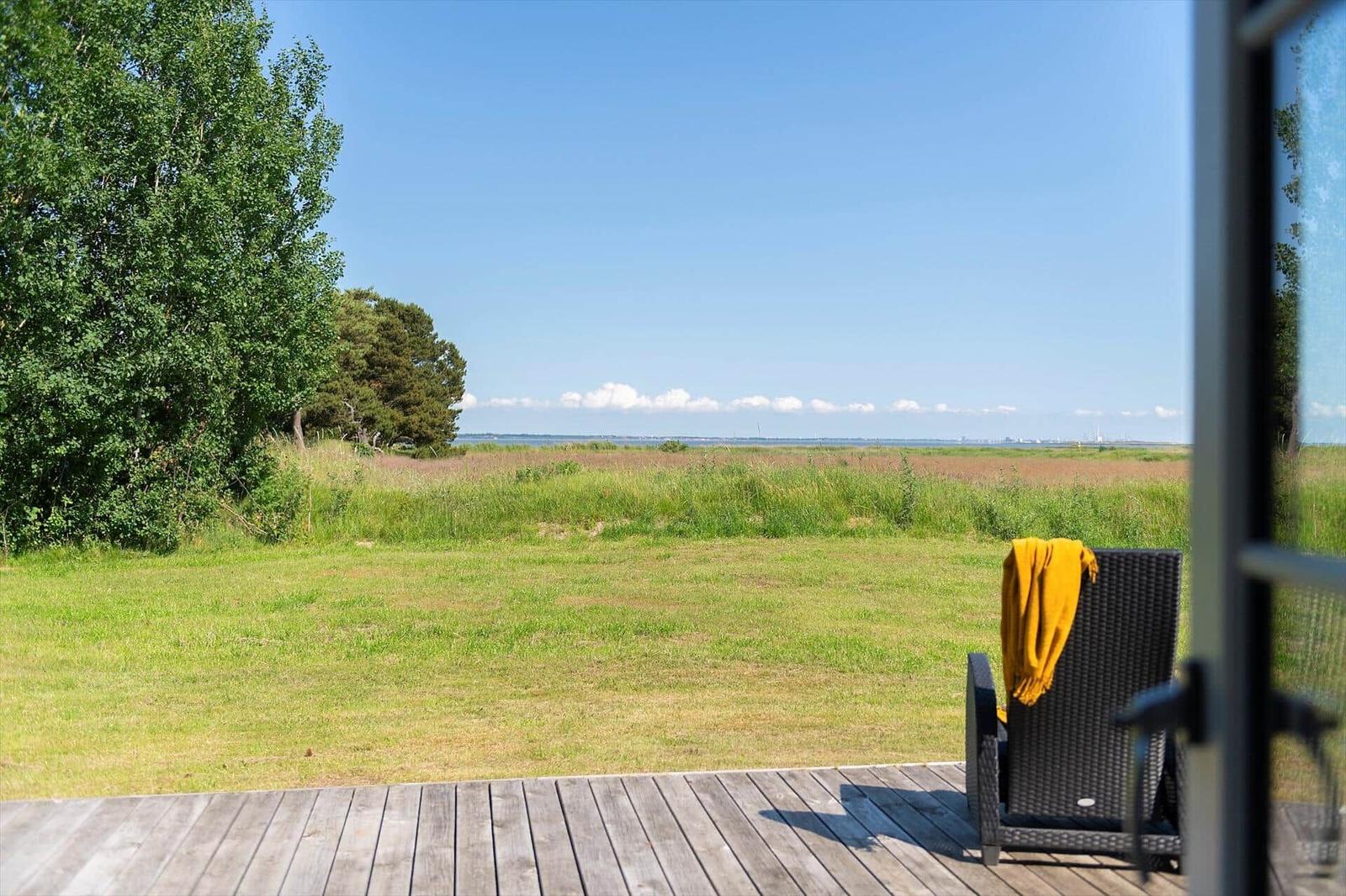 Terrasse mit Sitzgelegenheit und Blick auf Grünland und Horizont.
