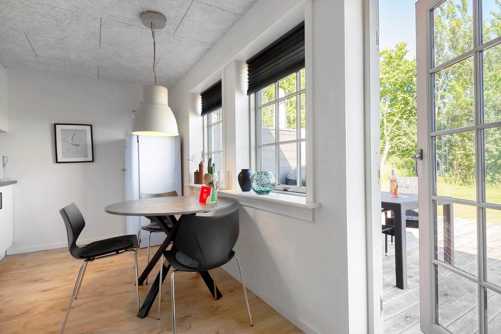 Essbereich mit Tisch und Stühlen, Fenster und Tür zum Garten.