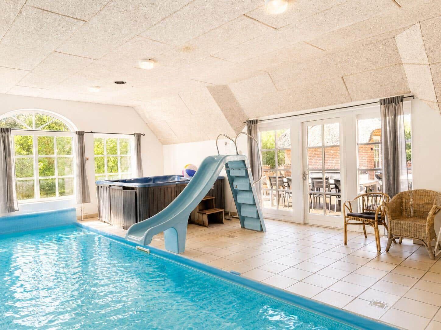 Innenpool mit Rutsche und Whirlpool, großzügiger Raum mit Fenstern und Terrasse.