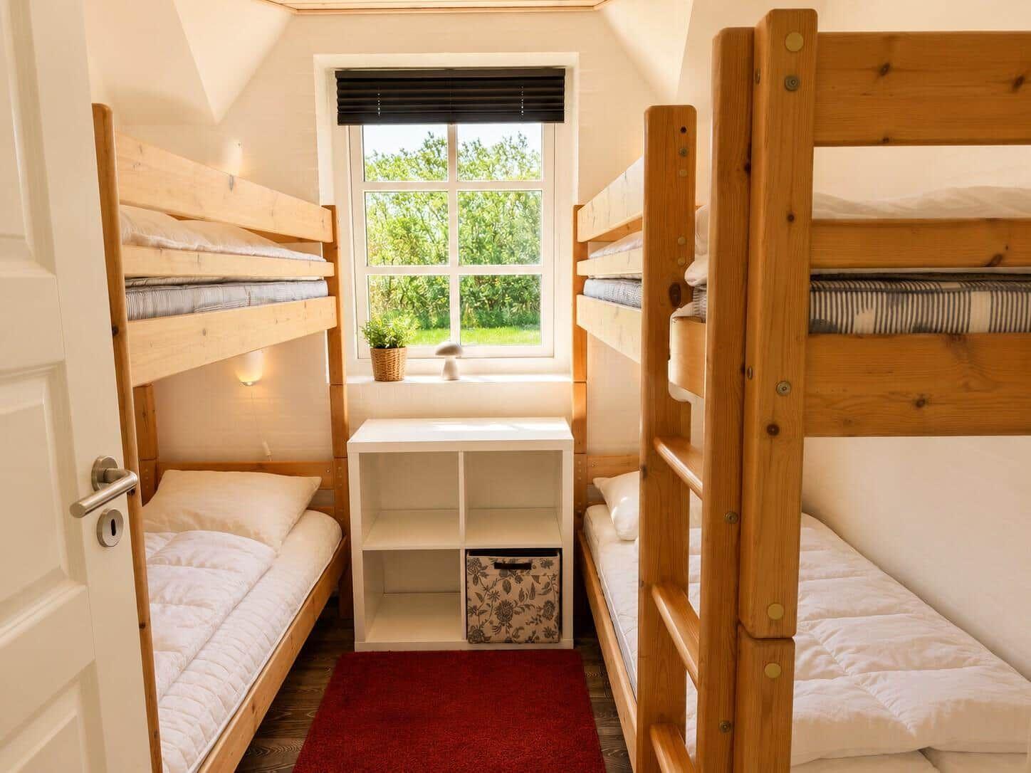 Zimmer mit zwei Holzbetten, Fenster und kleinem Regal.
