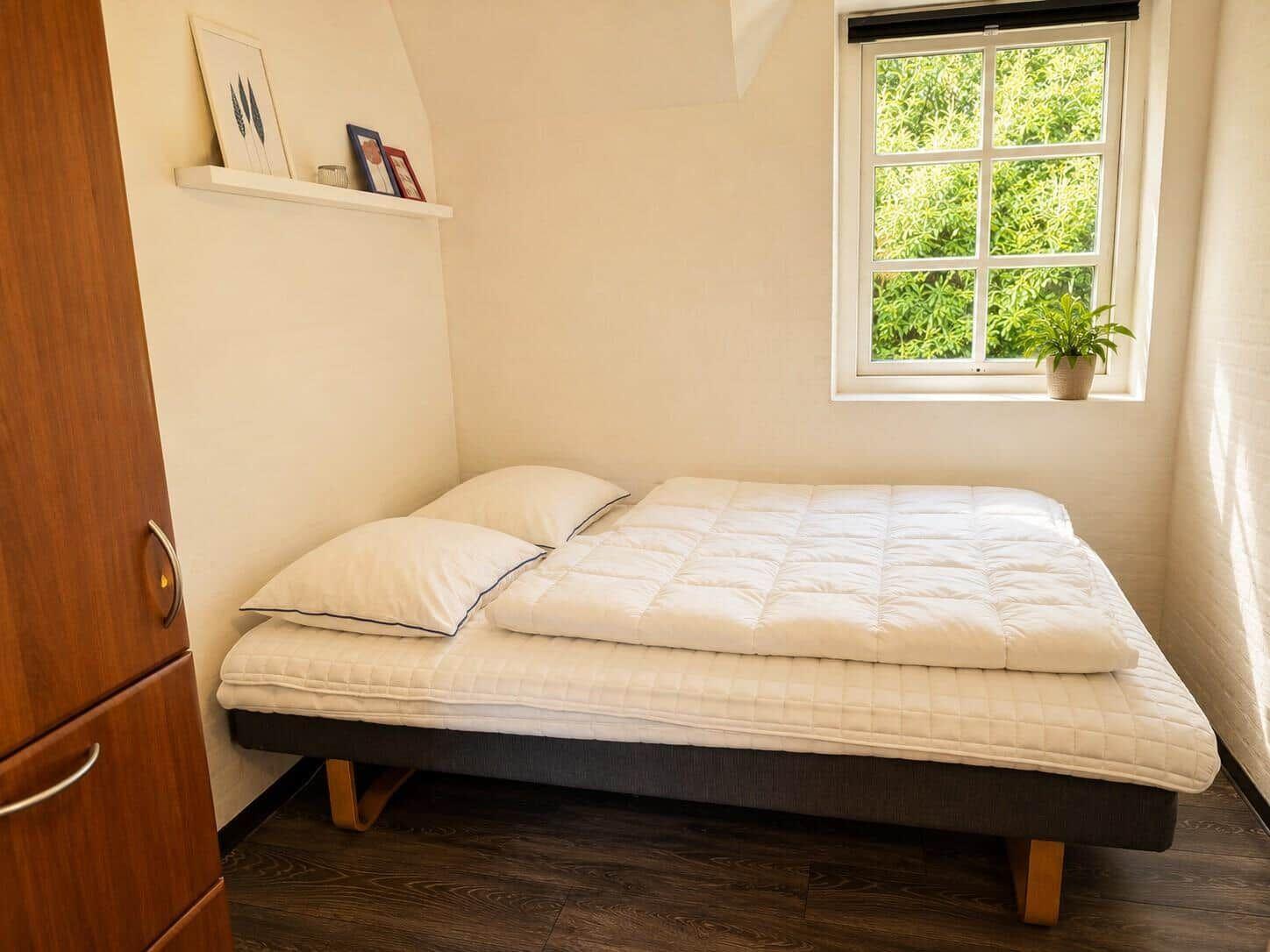 Ein Schlafzimmer mit Bett, Fenster und Kleiderschrank.