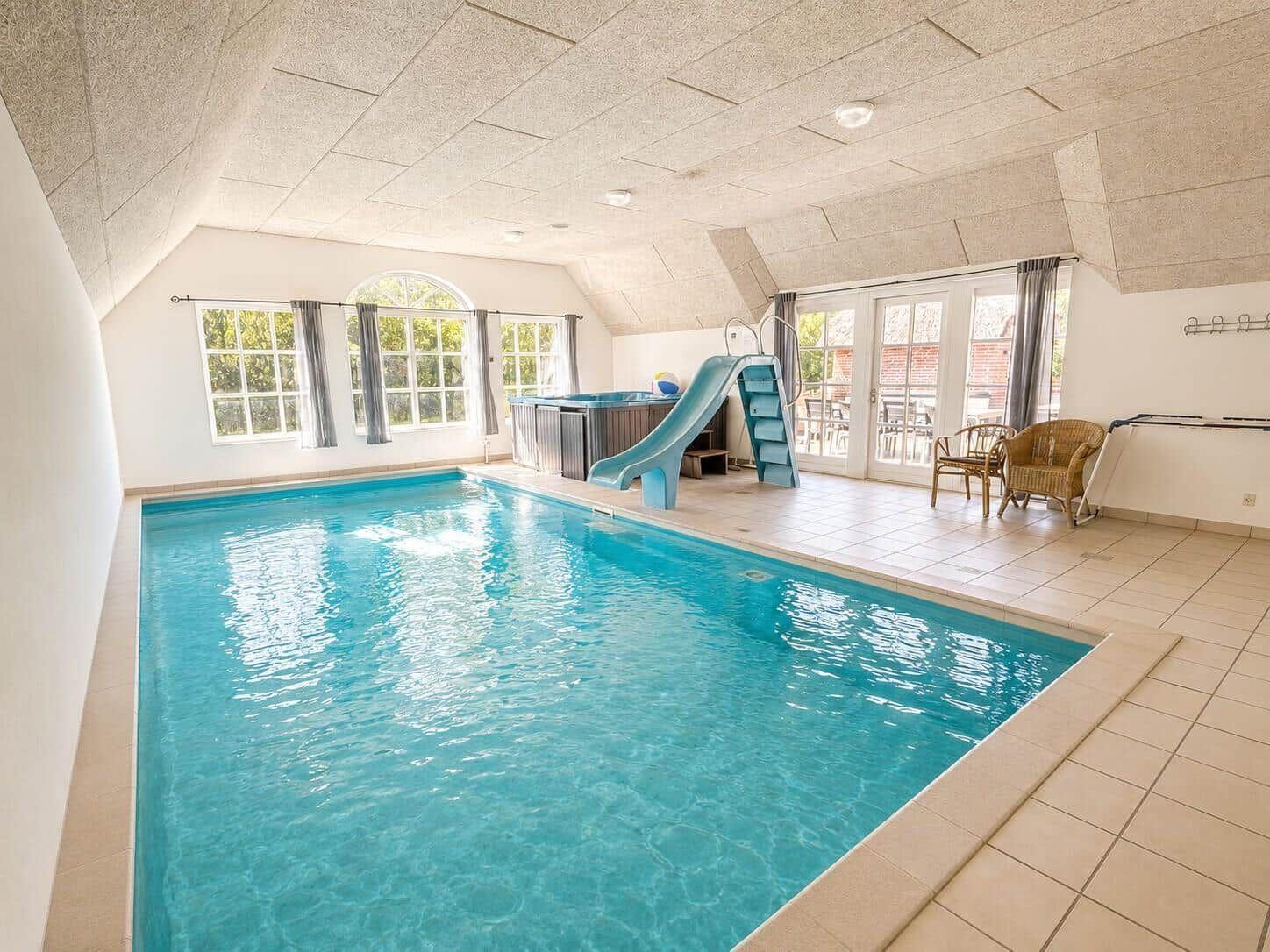 Innenpool mit Rutsche und Whirlpool, große Fenster und Terrasse.