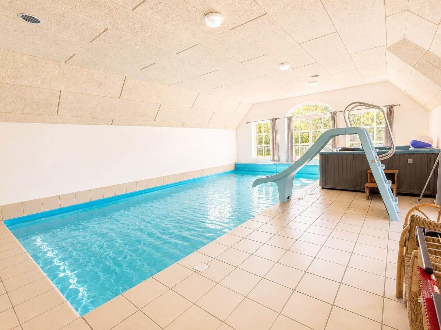 Indoorpool mit Rutsche und Whirlpool. Tageslicht durch Fenster.