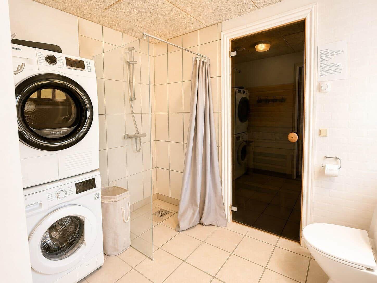 Dusche mit Duschvorhang, Waschmaschine und Trockner im Bad