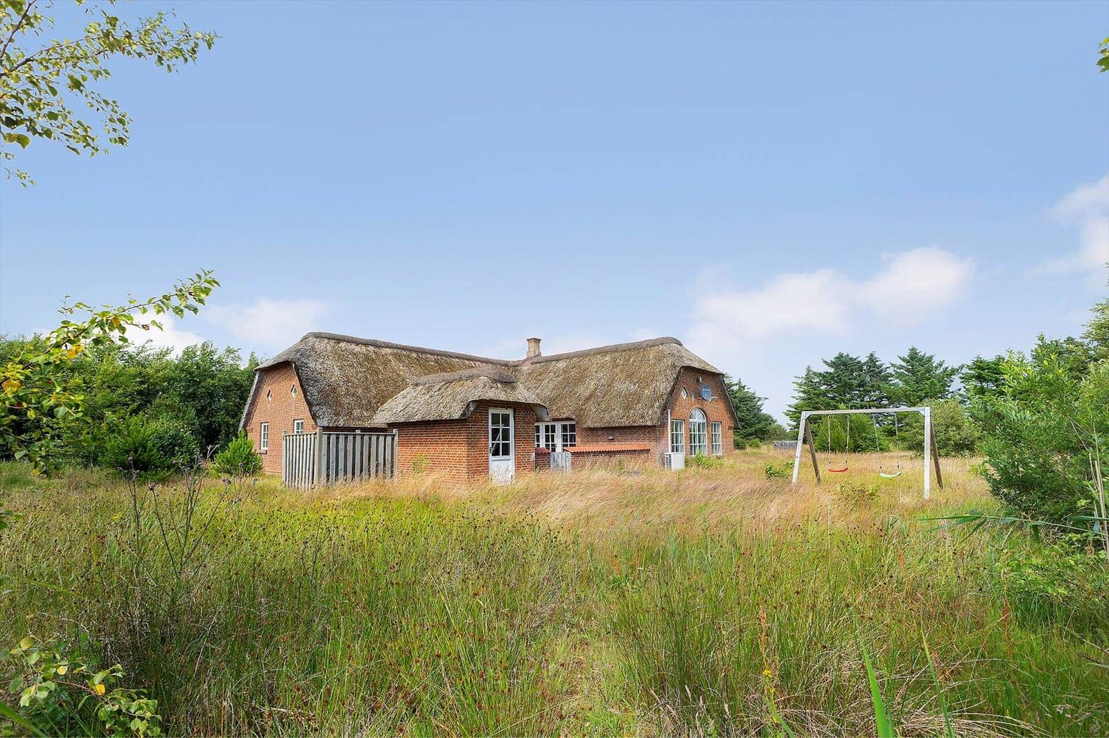 Haus mit Strohdach und Spielplatz im Grasland.