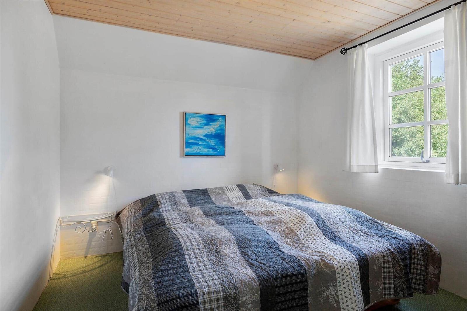 Schlafzimmer mit Bett, Fenster und Wandbild.