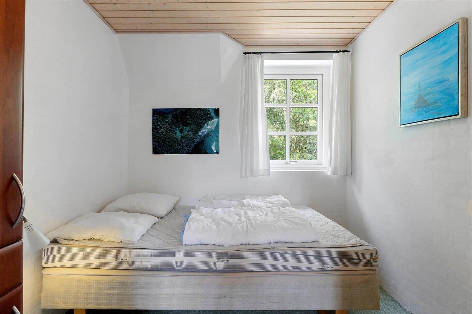 Schlafzimmer mit Bett, Fenster und Wandbildern