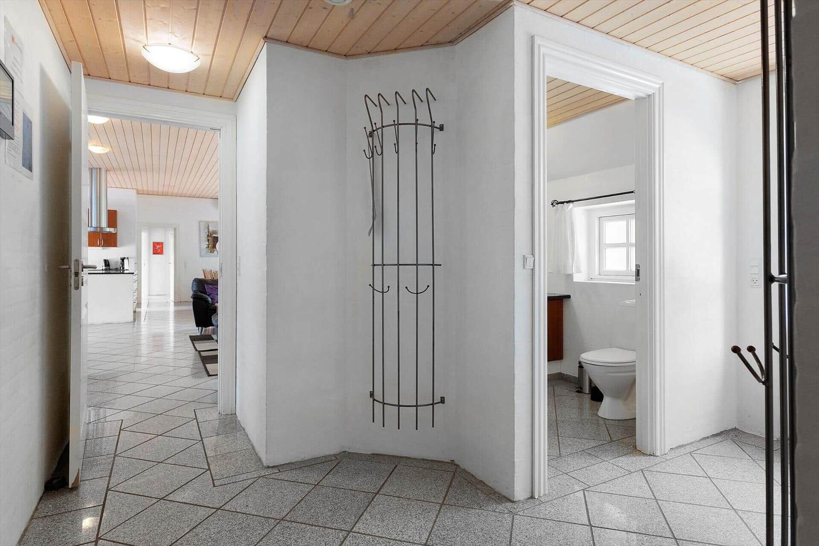 Flur mit Garderobe, Blick in Küche und Badezimmer mit Toilette.