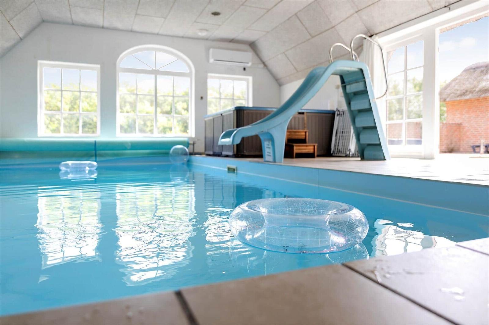 Innenpool mit Rutsche und Schwimmringen. Große Fenster und Dachfenster.
