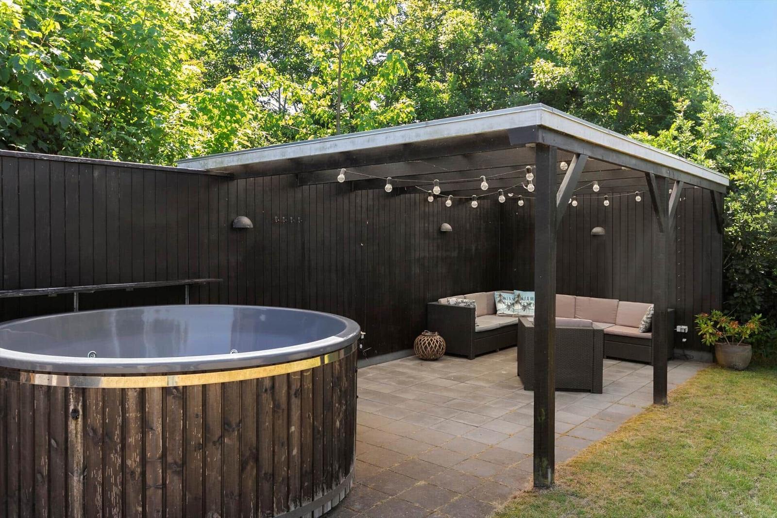 Hinterhof mit Whirlpool, Sitzgruppe unter Pavillon und Beleuchtung.