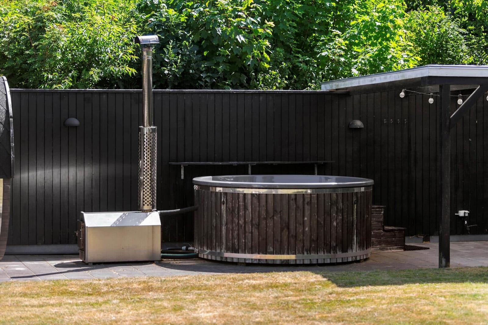 Hochwertiger Whirlpool mit Holzrahmen und Metallverkleidung im Gartenbereich.