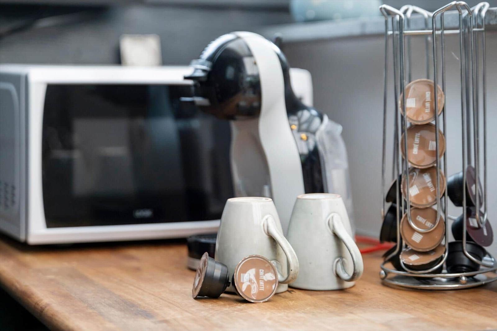 Kaffeemaschine mit Kapseln und Tassen auf Küchenarbeitsfläche