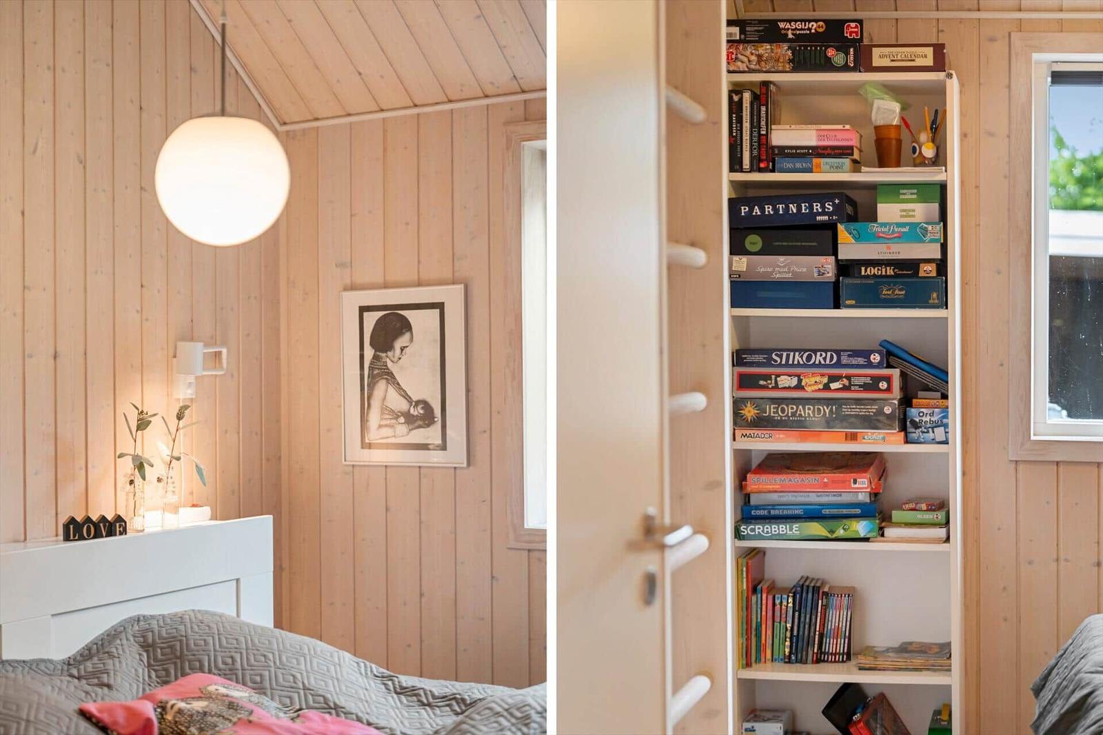 Schlafzimmer mit Holzwand, Bett und Bücherregal mit Spielen.