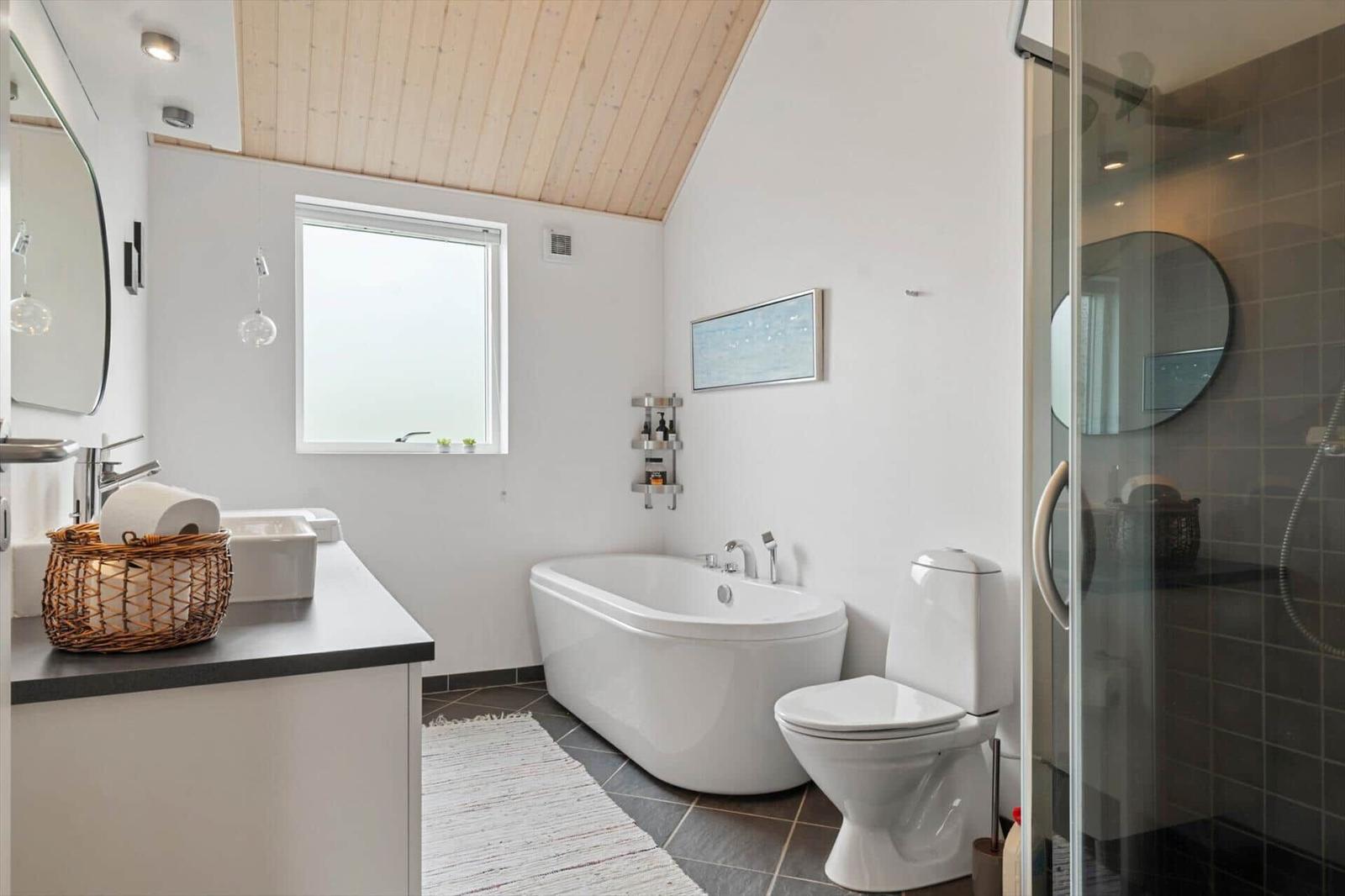 Badezimmer mit freistehender Badewanne, Dusche und Waschbecken mit Spiegel.