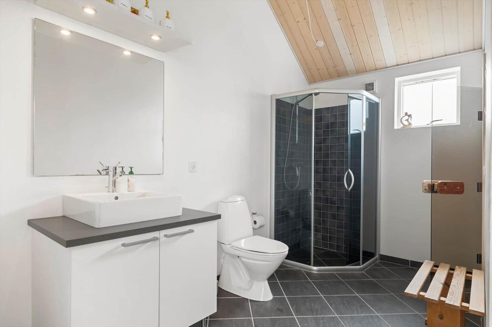 Badezimmer mit Dusche, Toilette und Waschbecken unter Spiegel.