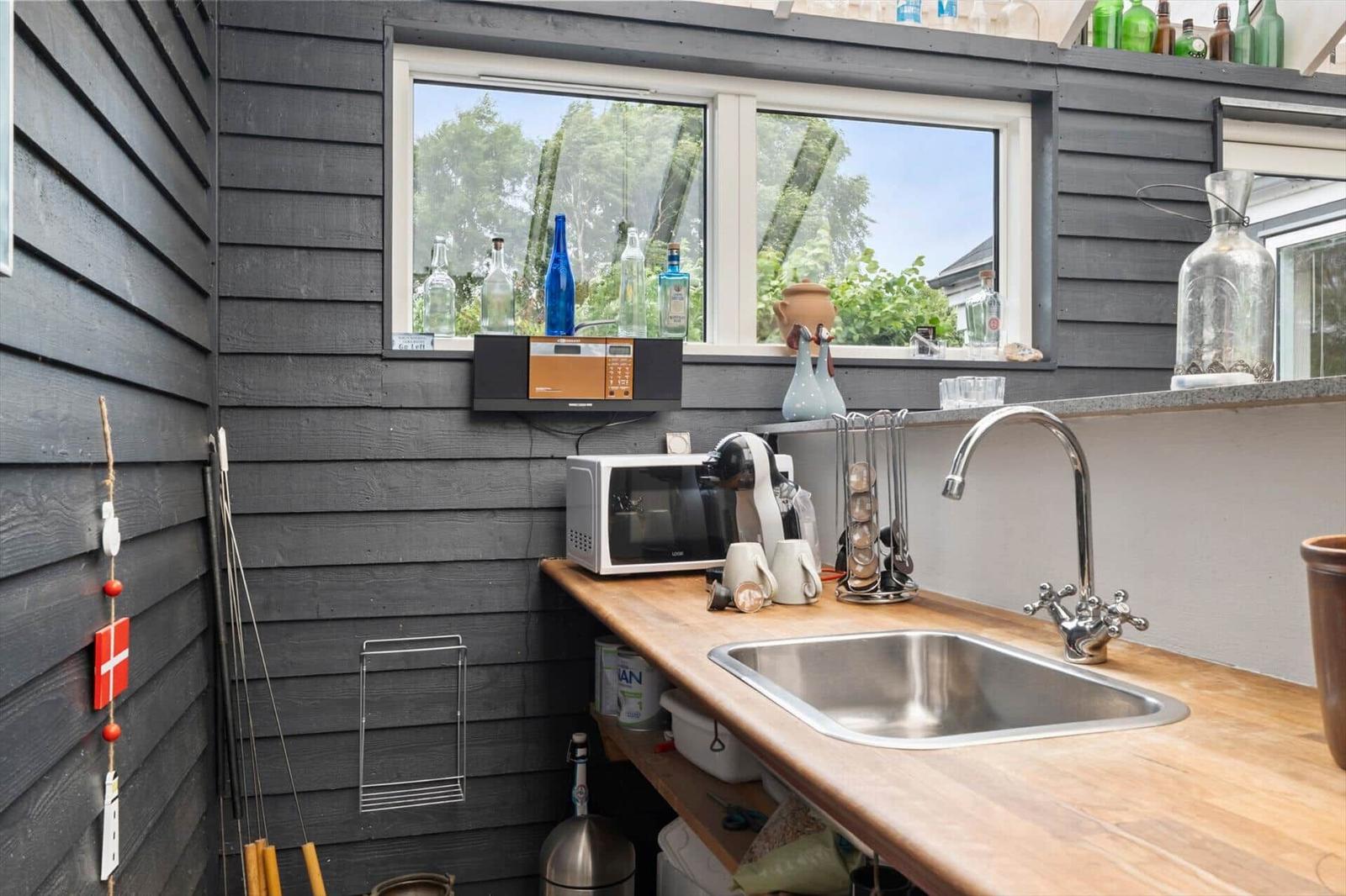 Küche mit Holzplatte, Spüle und Fenster mit Blick auf Grün.