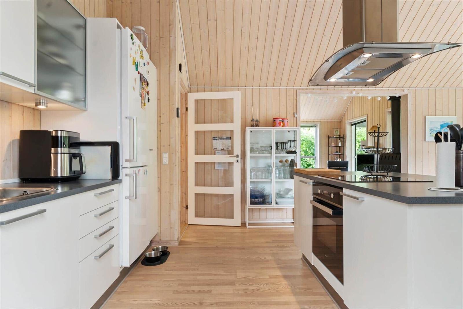Moderne Küche mit weißen Schränken, Holzboden und Holzwandverkleidung.