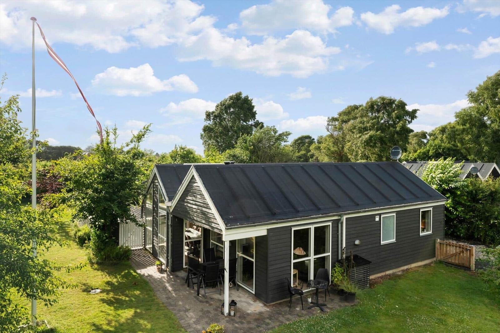 Ein modernes Haus mit Terrasse und Garten unter blauem Himmel.