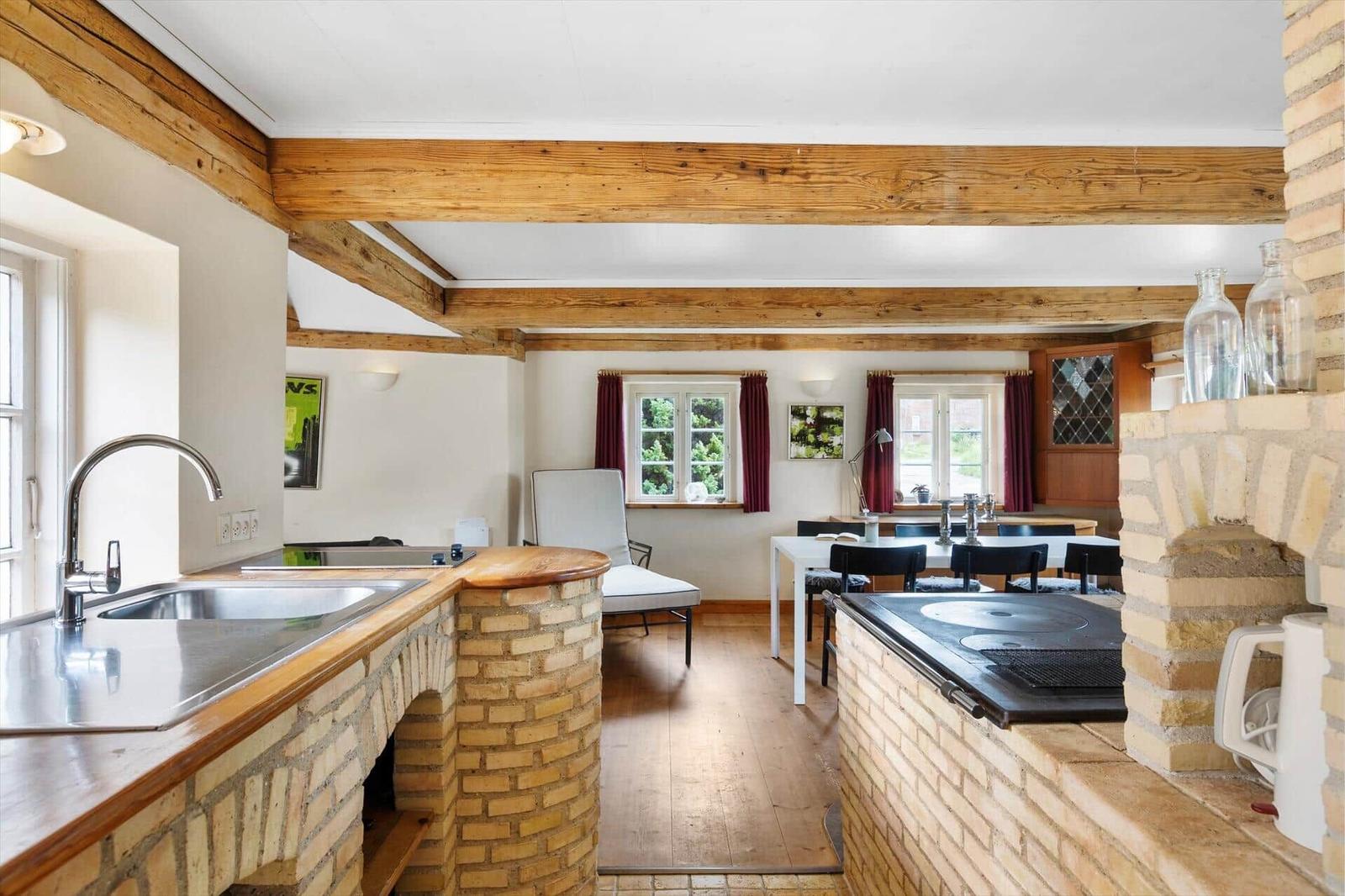 Küche mit Steinwand, Essbereich und Holzbalken an der Decke.