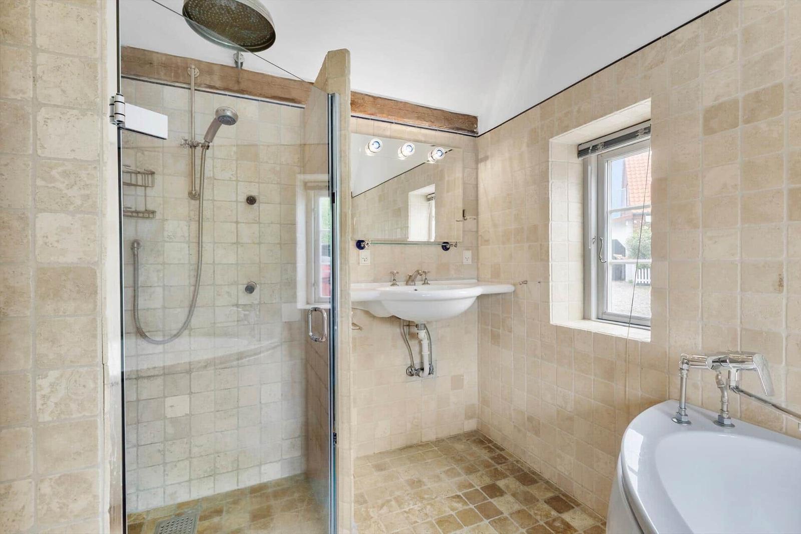 Badezimmer mit Dusche, Waschbecken und Badewanne. Fliesenwand und Fenster.