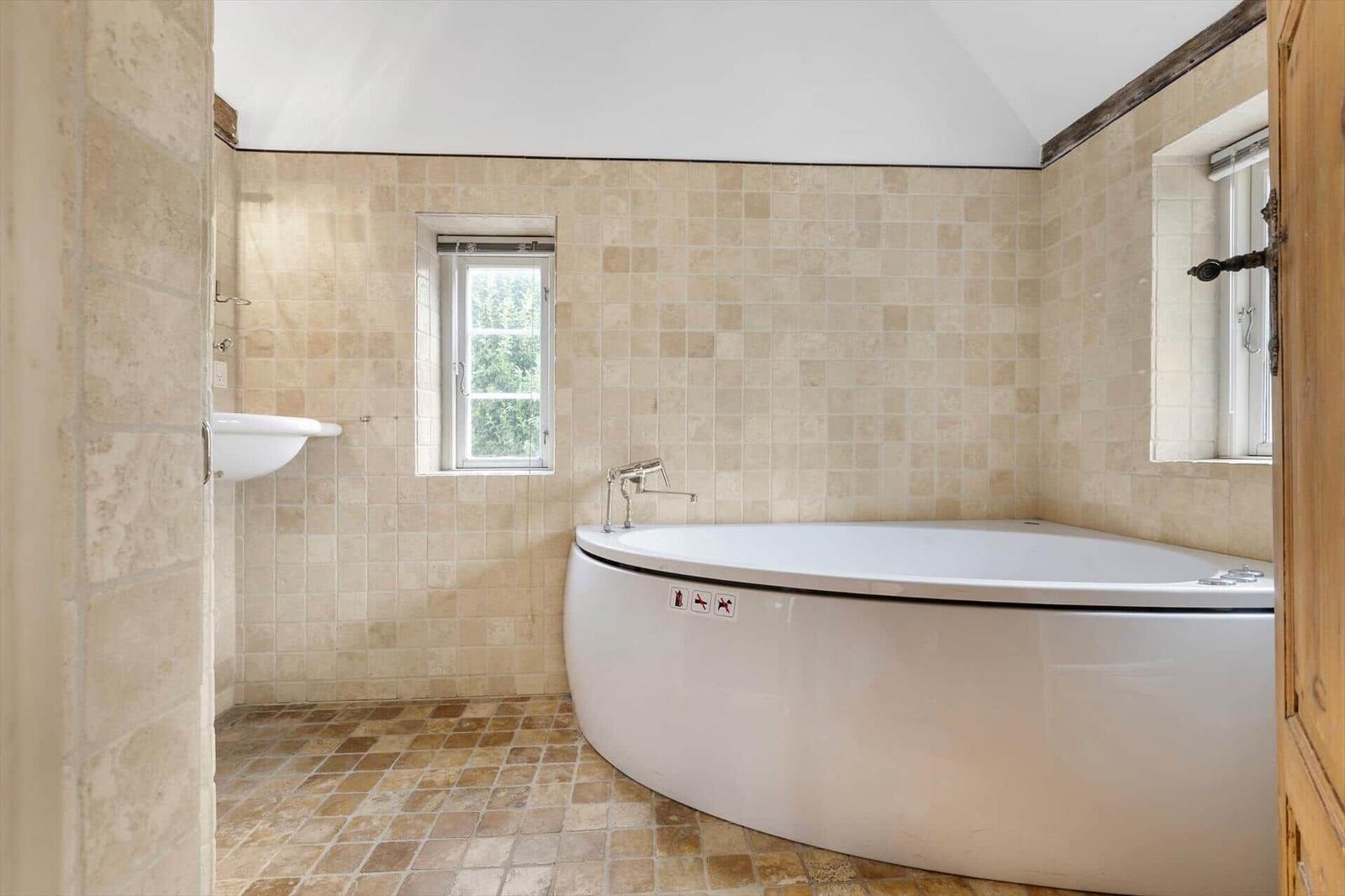 Bad mit Badewanne, Waschbecken und Fenstern