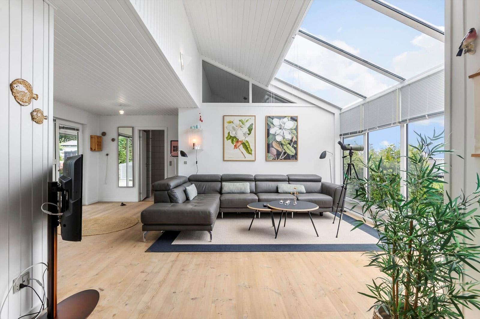 Wohnzimmer mit grauem Sofa, Holzboden und großem Dachfenster.