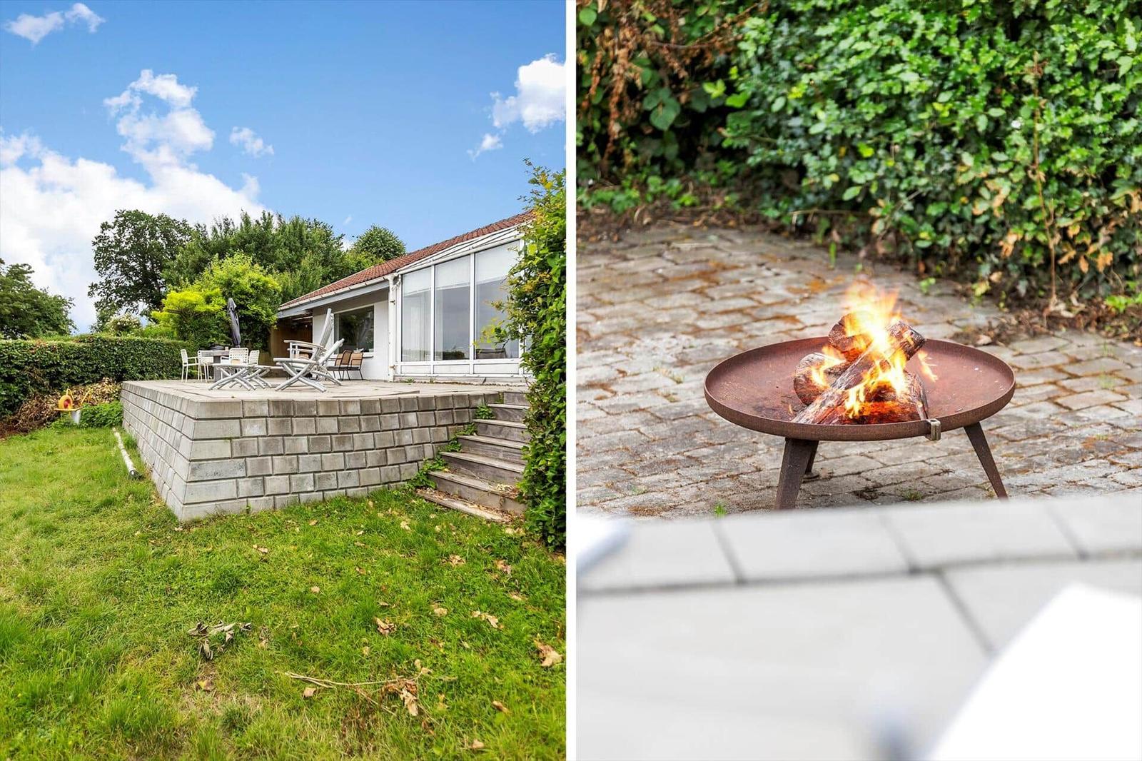 Haus mit Terrasse und Grillplatz im Garten. Feuer brennt im Feuerkorb.