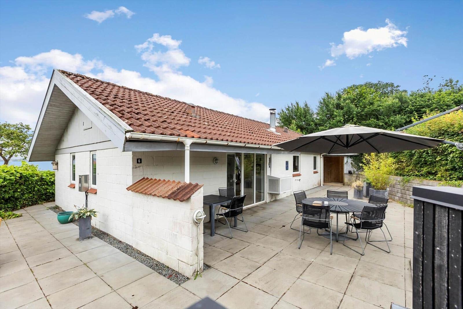 Wohnhaus mit Terrasse, Sitzgruppe und Sonnenschutz. Hinterhof mit Grünflächen.