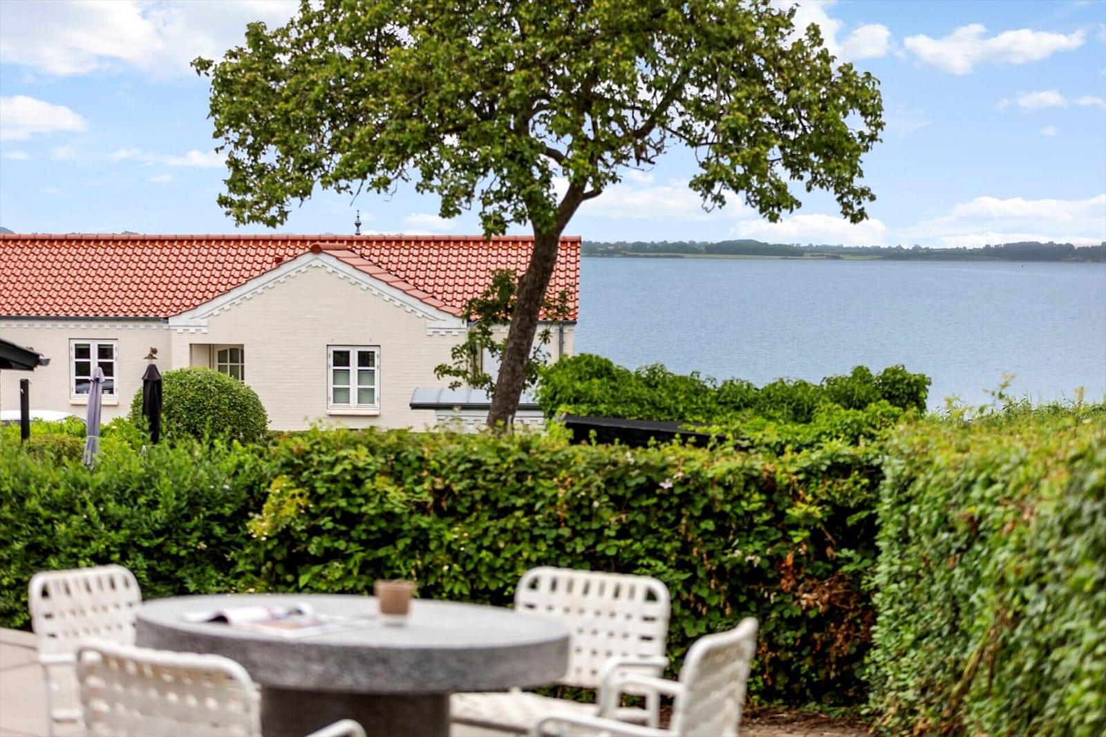 Haus mit Blick auf See, Gartenbereich mit Tisch und Stühlen.
