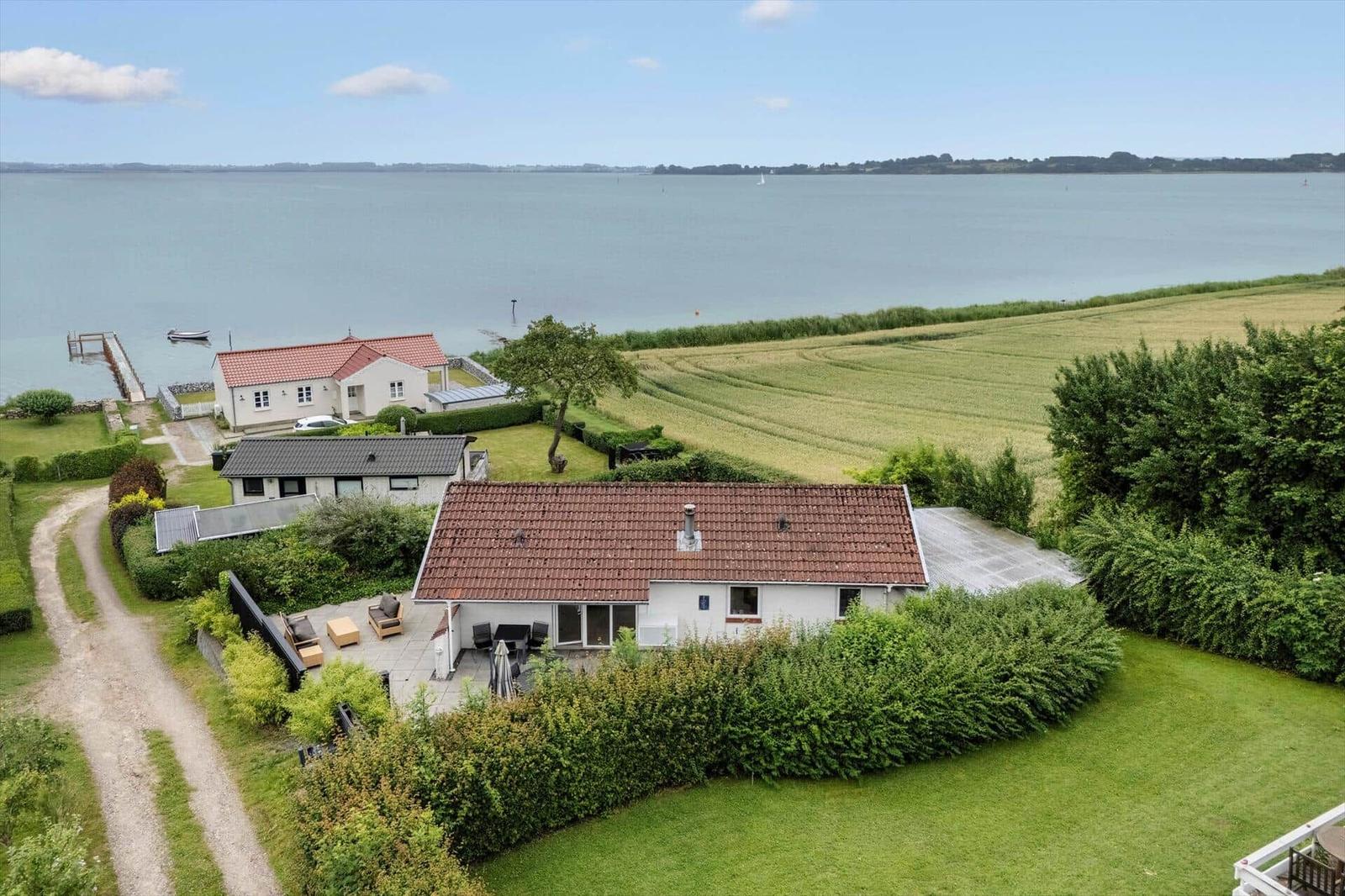 Wohnhaus mit Terrasse, umgeben von Grünflächen und einem See.