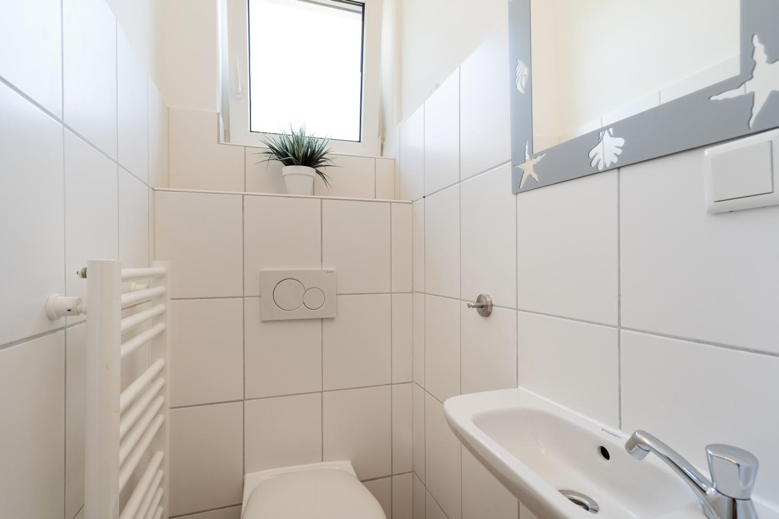 Badezimmer mit Toilette, Waschbecken und Spiegel mit Muschel- und Sternenmotiven.