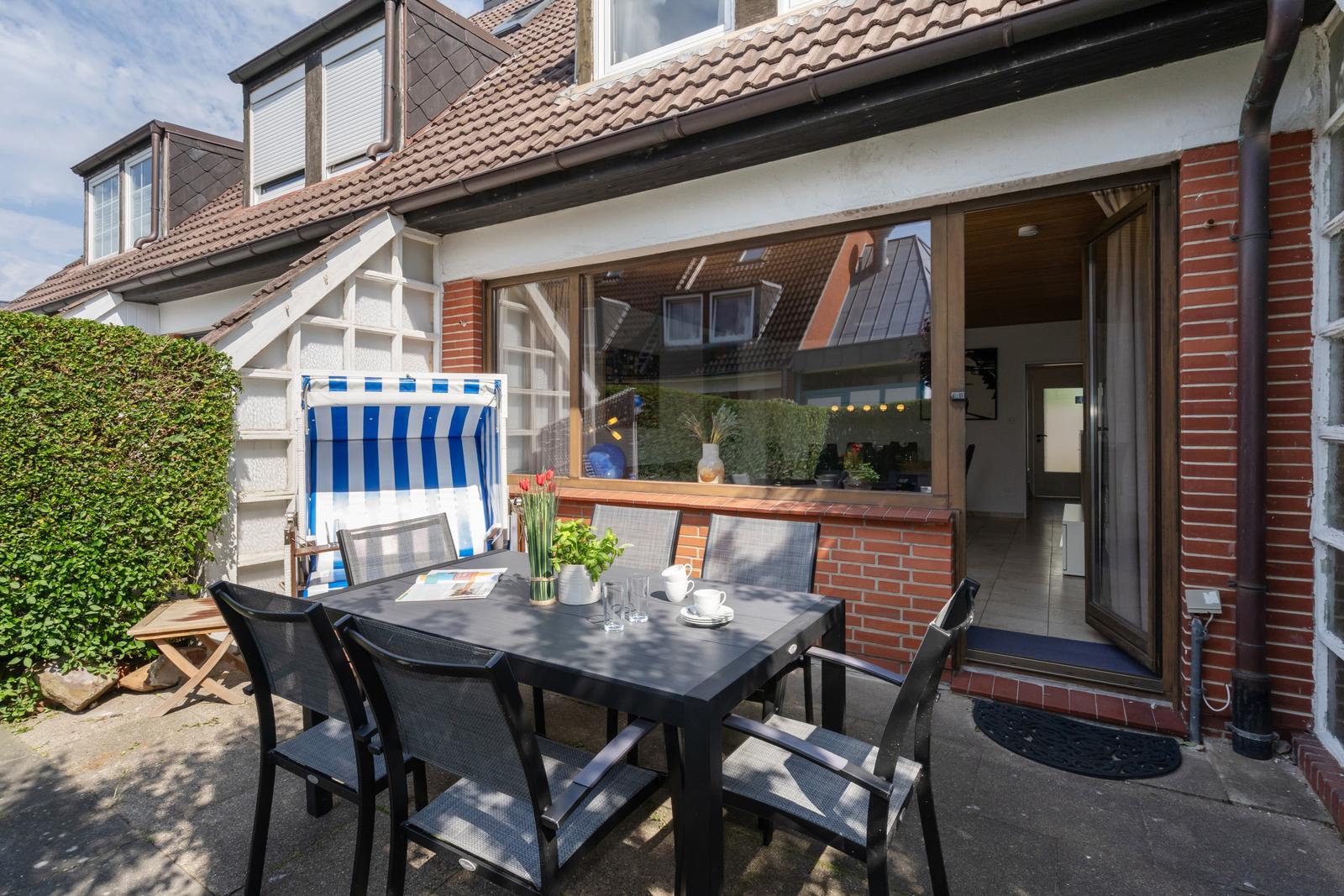 Terrasse mit Tisch, Stühlen und Liegestuhl. Durchgang ins Haus. Blick auf Wohnbereich.