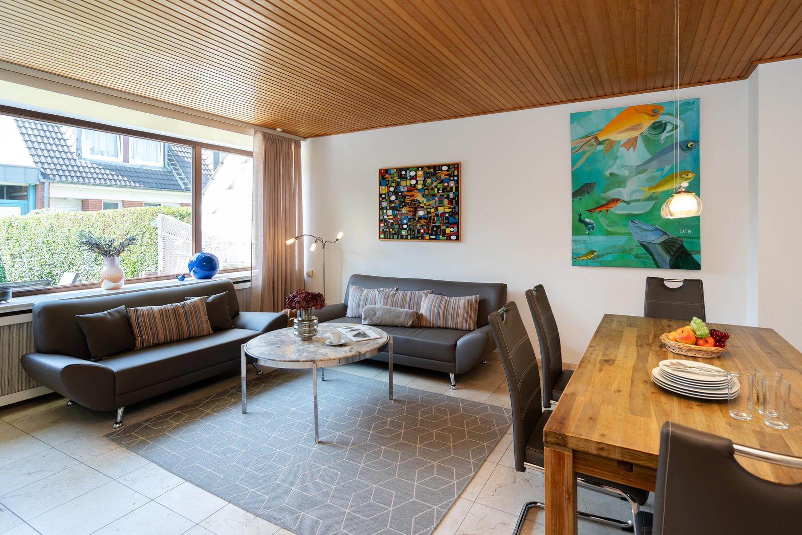Wohn- und Essbereich mit Sofa, Esstisch und Wandbildern.
