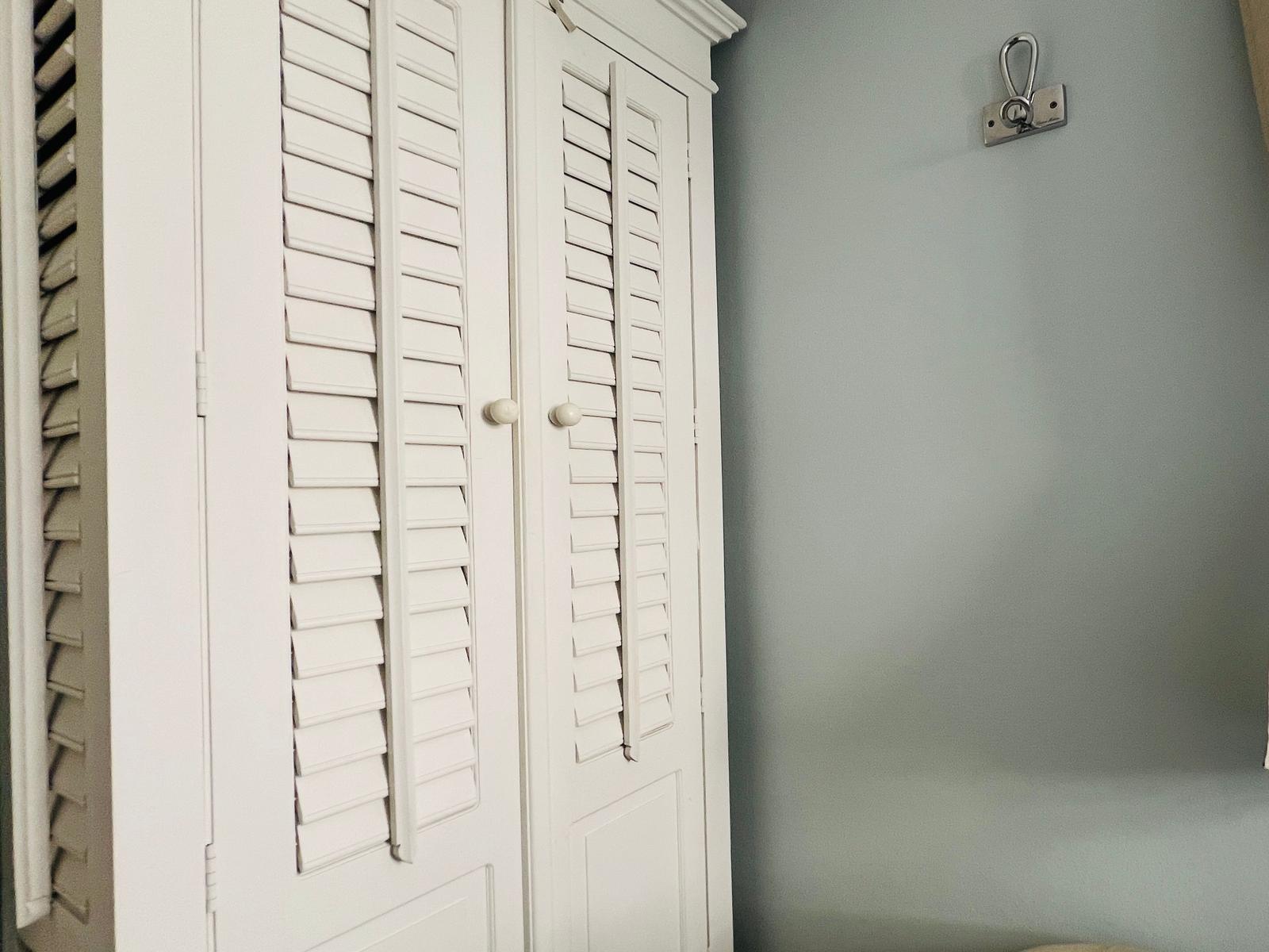 Weißer Schrank mit Jalousien und Wandhalterung
