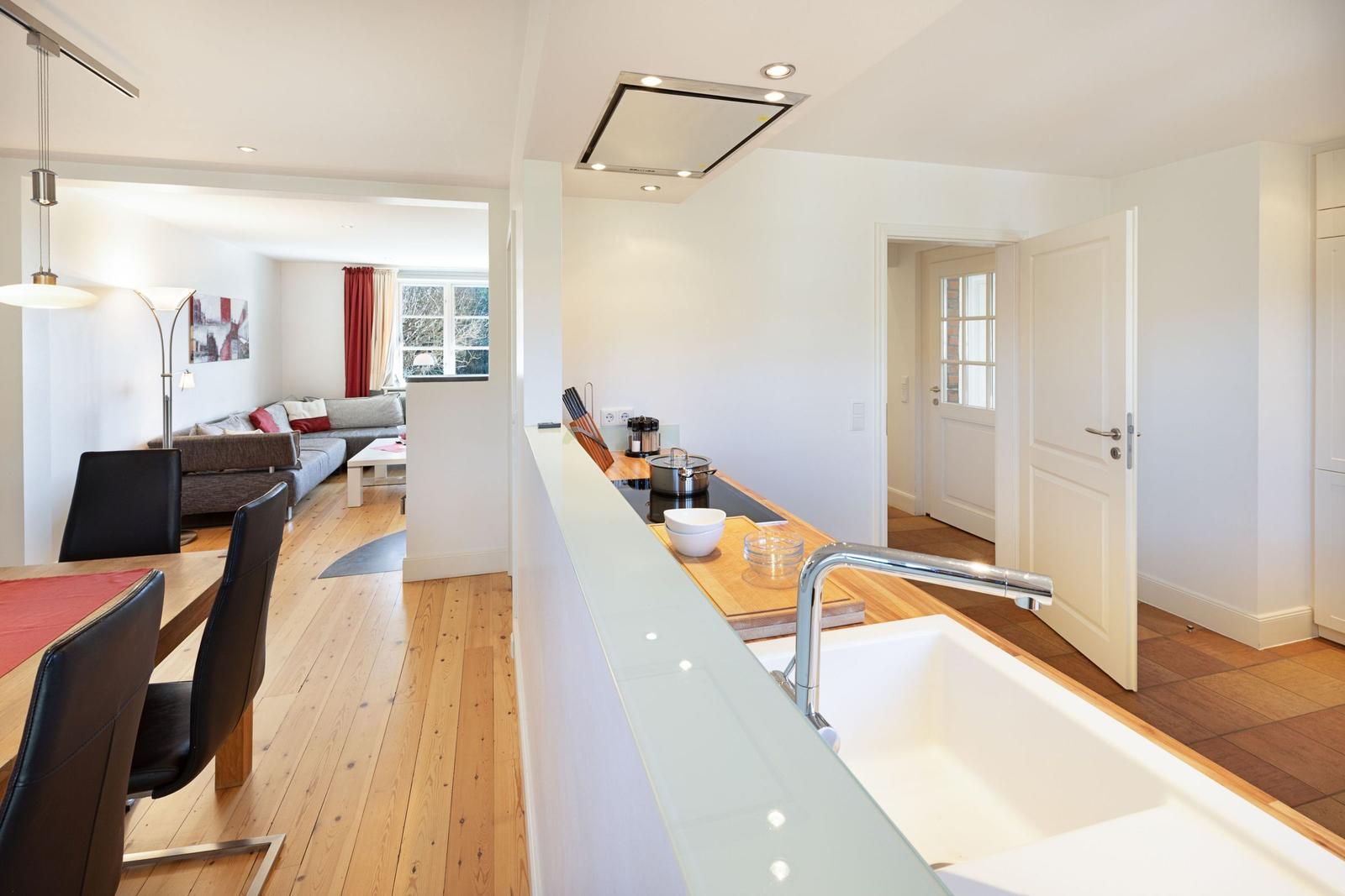 Küche mit Arbeitsplatte und Spüle. Blick in Wohnzimmer mit Sofa und Fenster.
