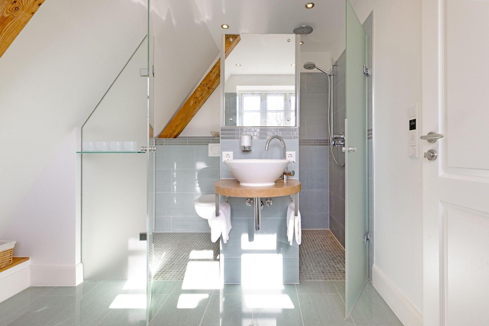 Badezimmer mit Dusche, Waschbecken und Toilette unter Holzdecke.