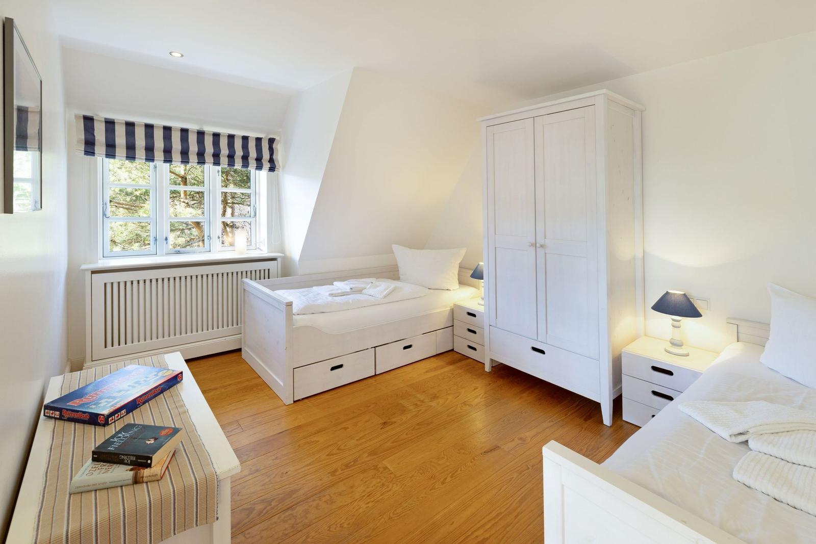 Zimmer mit zwei Betten, Schrank und Fenster mit Blick auf Bäume.
