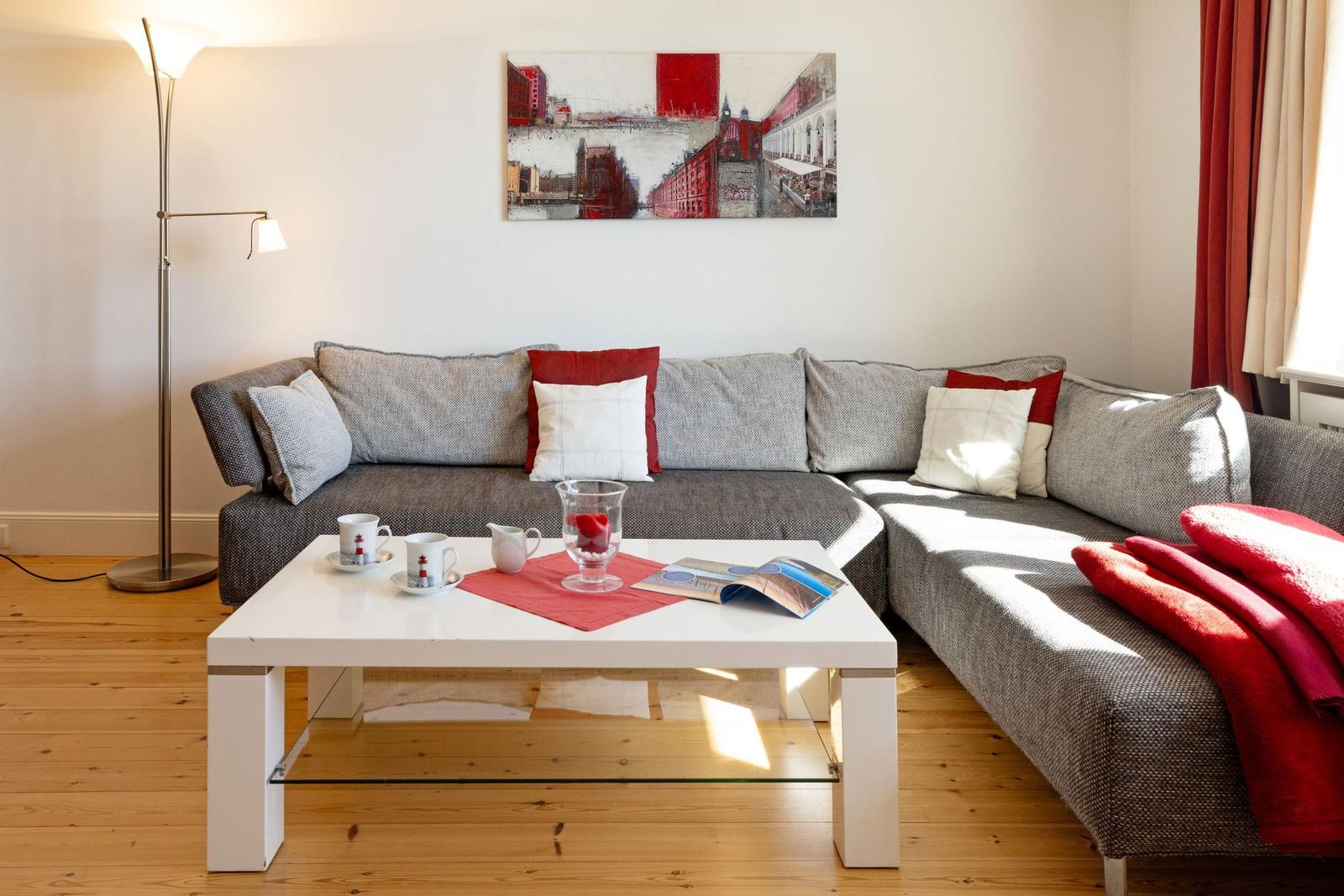 Ein Wohnzimmer mit grauem Sofa, rotem Teppich und weißem Couchtisch.