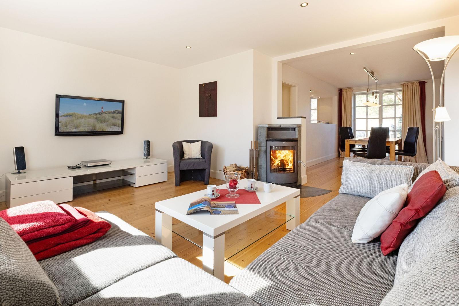 Wohnzimmer mit Kamin, Sofa, Fernseher und Essbereich im Hintergrund.