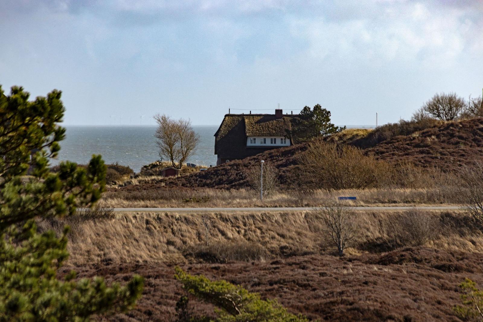 Haus auf Hügeln mit Blick auf Meer und Windkraftanlagen