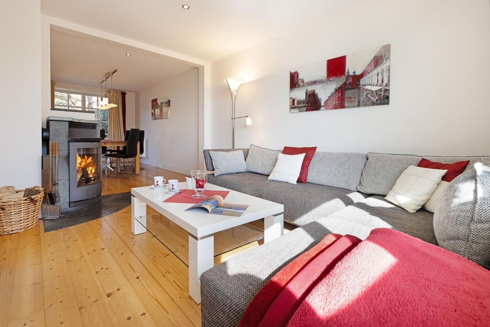 Wohnzimmer mit Sofa, Kamin und Tisch. Wandbild und Holzboden sichtbar.
