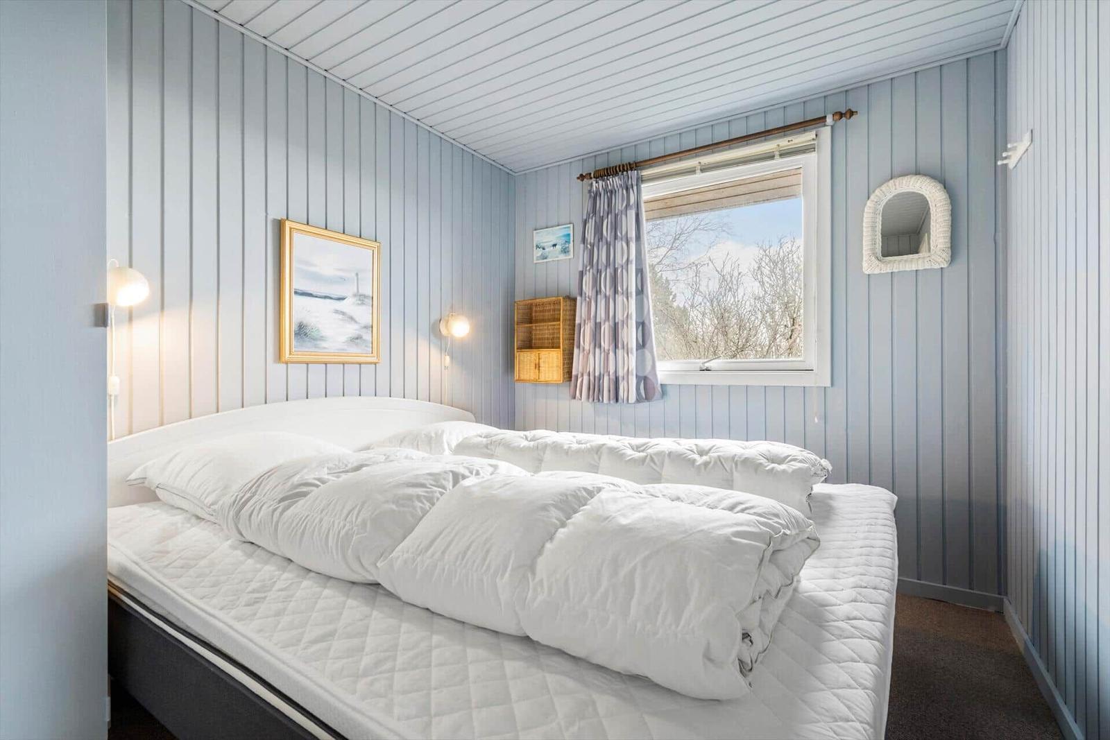 Schlafzimmer mit Bett, Fenster und Wanddekoration.