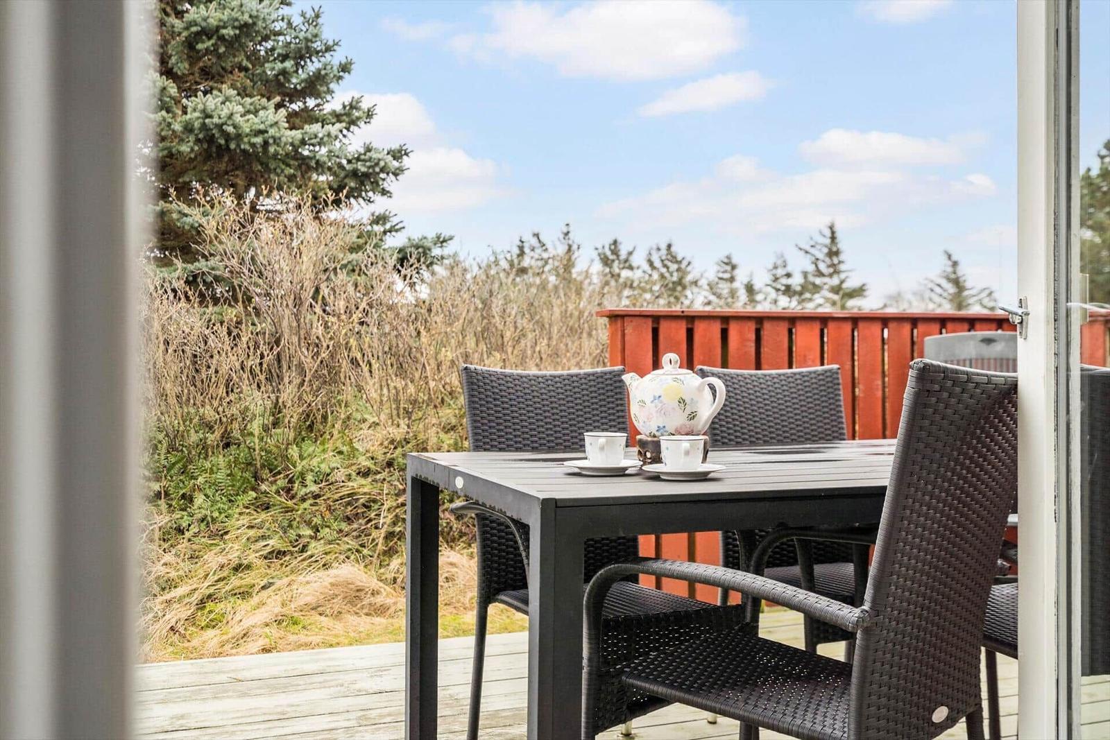 Terrasse mit Tisch und Stühlen, Blick auf Bäume und Himmel