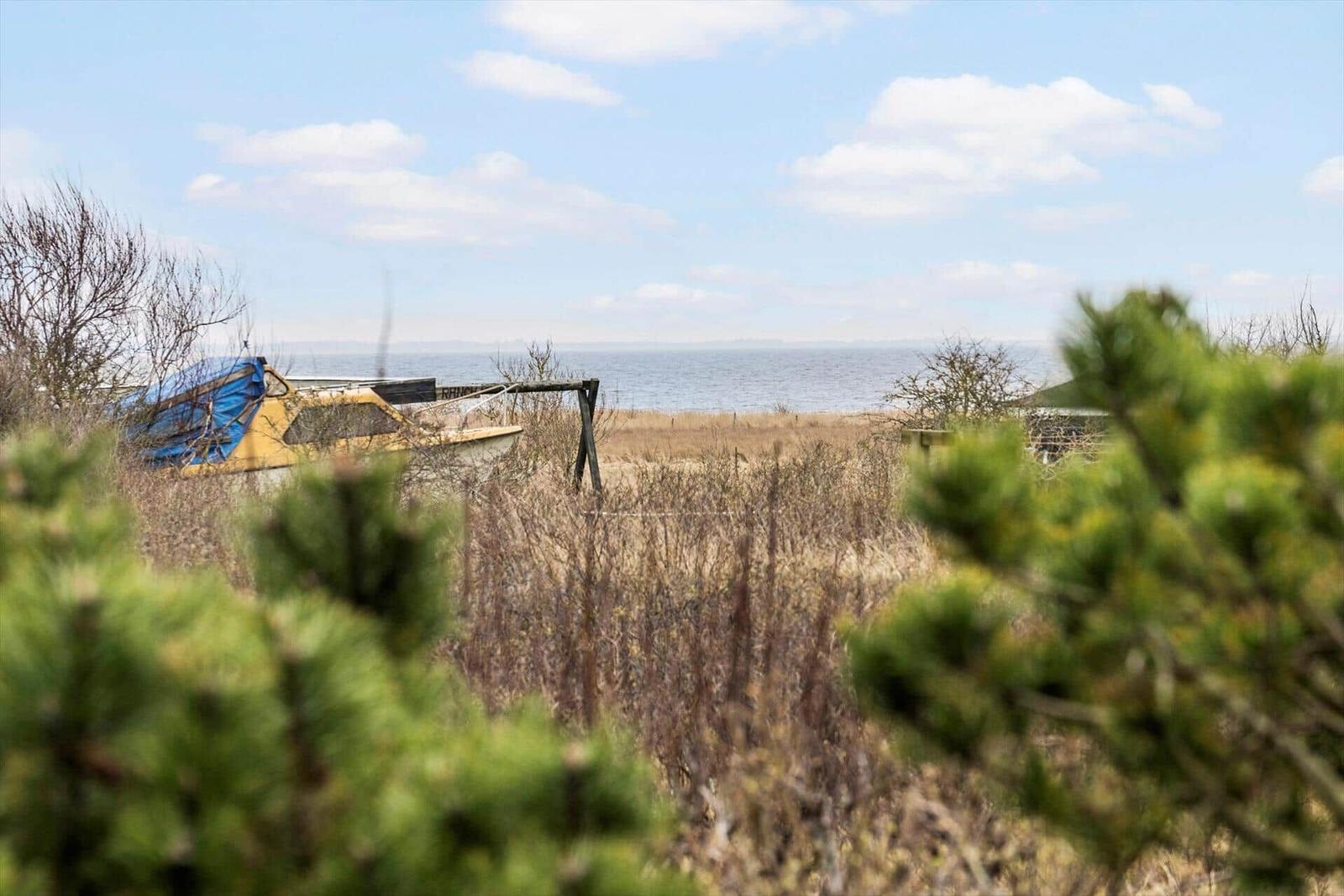 Boot liegt am Strand, Blick aufs Meer durch trockenes Gras.