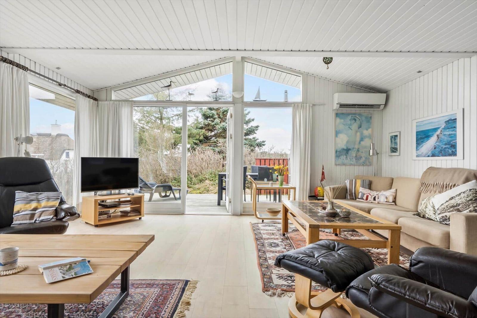 Wohnzimmer mit Sofa, Fernseher und Blick auf die Terrasse.