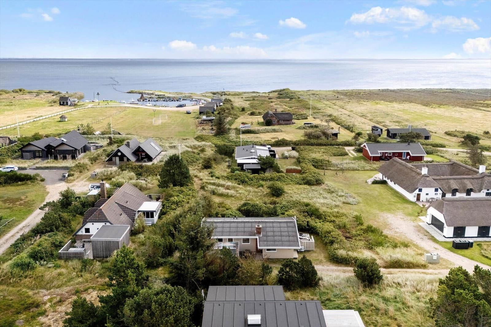 Häuser und Grünflächen am Strand mit Blick aufs Meer.