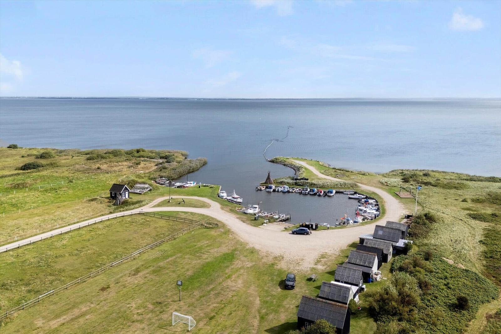 Hafen mit Booten, Grünflächen und kleineren Gebäuden an der Küste.