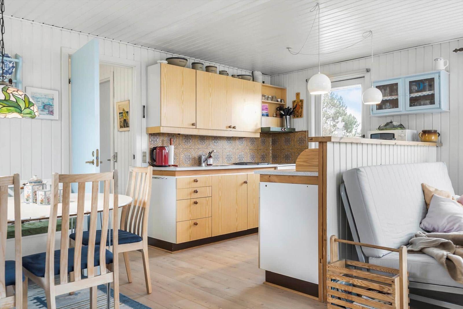 Küche mit Holzschränken, Esstisch und Sofa im Hintergrund.